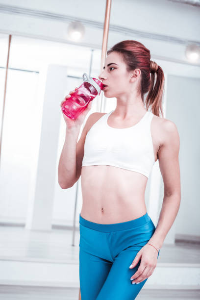 istock Red-haired pole dancer drinking water in order to stay hydrated 1059284032
