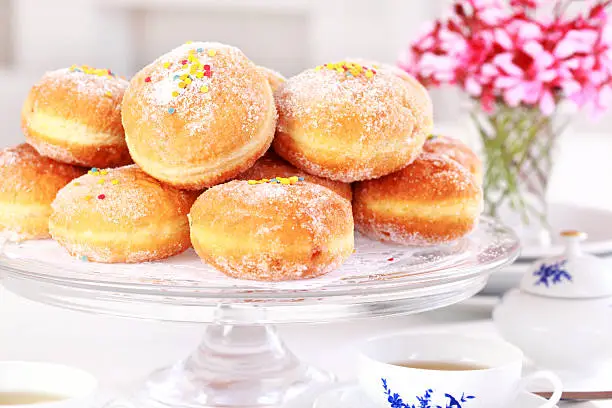 Doughnut filled with strawberry jam - German national dish with cup of tea