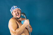 Funny fat man in blue cap sing in the shower