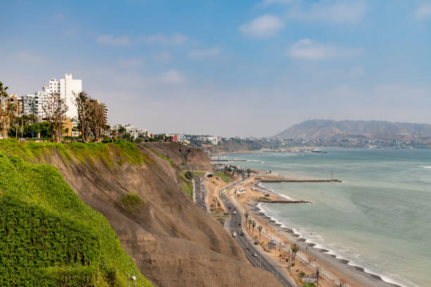 View along the coast of the Miraflores district in Lima, Peru, during a hot day in the spring. The beach and the highway meets the cliffs.