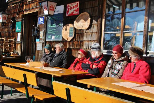 personas disfrutan el sol en la terraza de una cabaña de montaña en invierno. salzburgo, austria, europa. - apres ski ski restaurant mountain fotografías e imágenes de stock