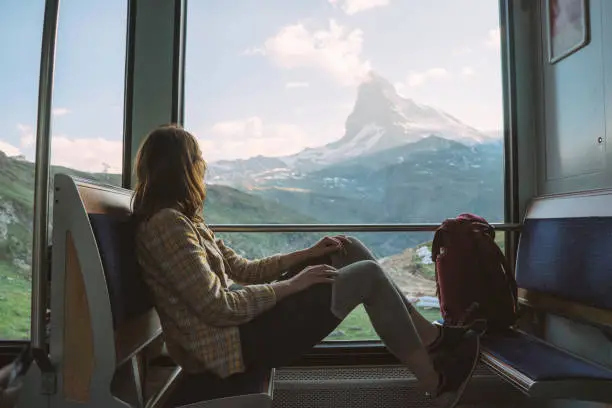 Young Caucasian woman traveling on the train near Matterhorn, Swiss Alps