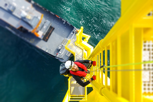 Alta trabajador manual offshore escalada en turbina de viento en escala photo