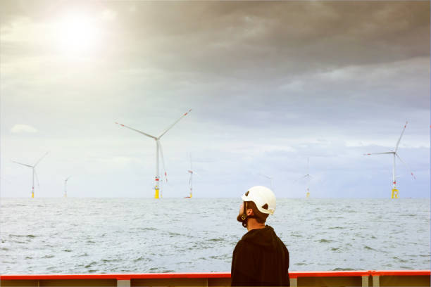 istock Manual worker offshore looking on wind-turbine from boat 1059319060