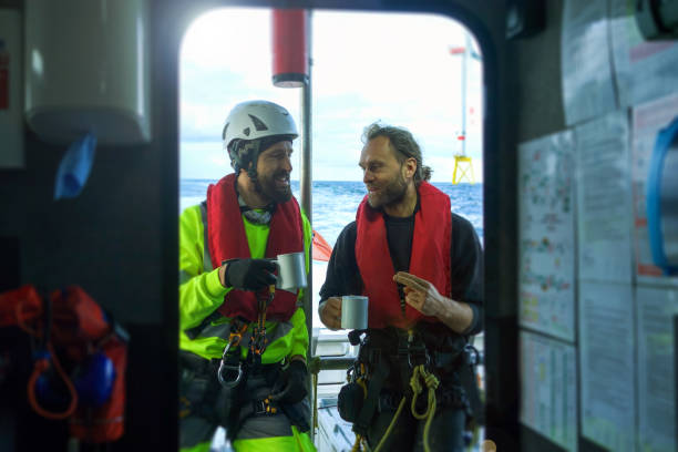 istock Two manual workers - technician offshore have break and enjoying morning cafe on transfer vessel 1059319242