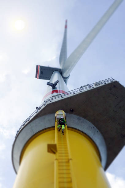 istock Manual high worker climbing on biggest wind-turbine offshore 1059321378