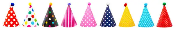 Row of nine colorful festive birthday party hats with different patterns and pom-poms