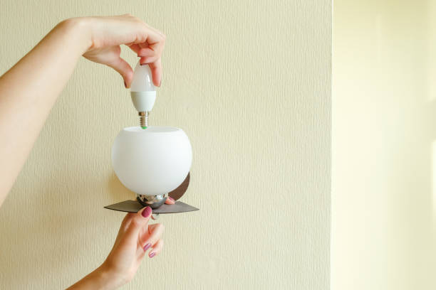 istock The girl changes the light bulb in the lamp. 1059329318