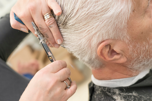 Portrait of senior men at the hairdresser cutting his hair. Face not visible.