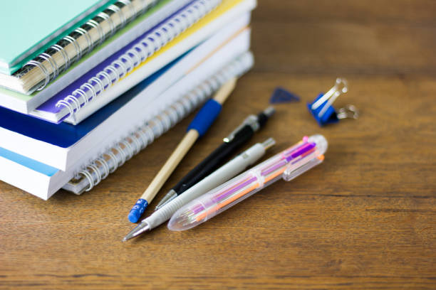 istock Stack of notebads and pens on wooden table. 1059336180