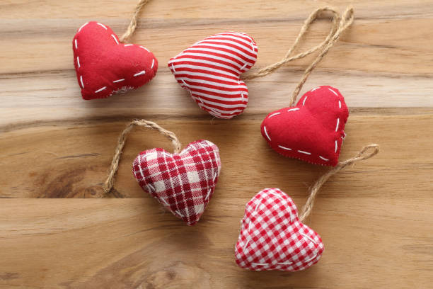 istock Valentine's Day: red striped, checkered and plain fabric handmade love heart on a wooden board 1059337146