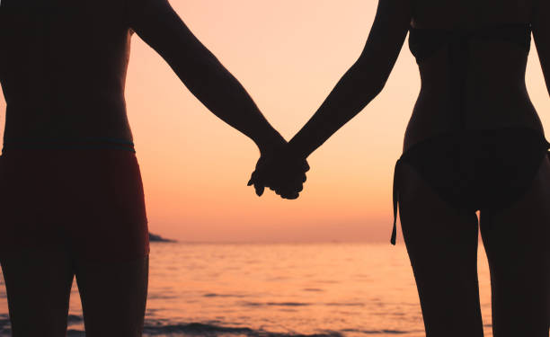 istock Couple holding hands at sunset beach, romantic vacation. 1059341626