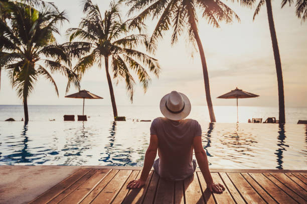 Holidays, tourist relaxing in luxury beach hotel near luxurious swimming pool. tourist in luxury beach hotel near luxurious swimming pool at sunset, tropical exotic holidays vacation, tourism and travel getting away from it all stock pictures, royalty-free photos & images