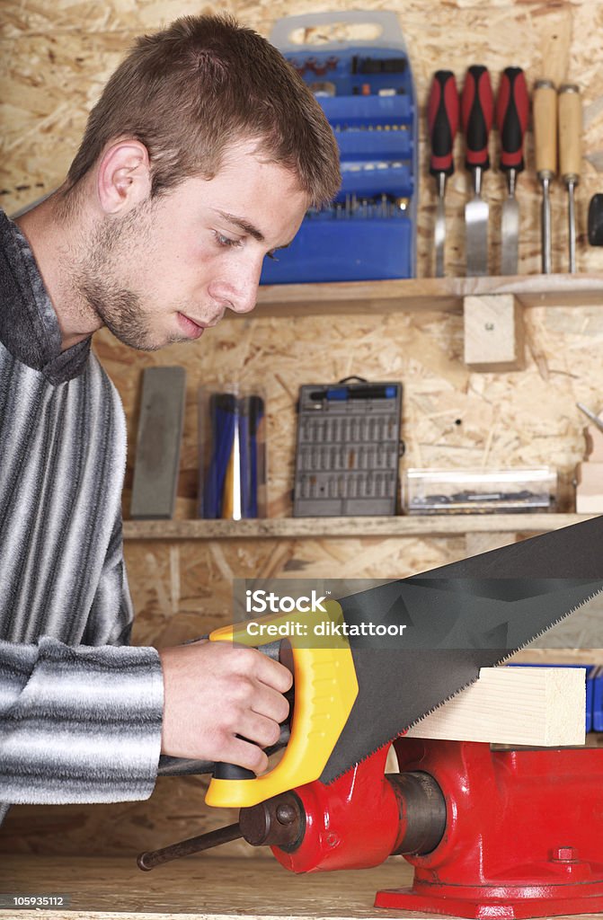 Young male sawing Young man is sawing wood in his lumber Activity Stock Photo