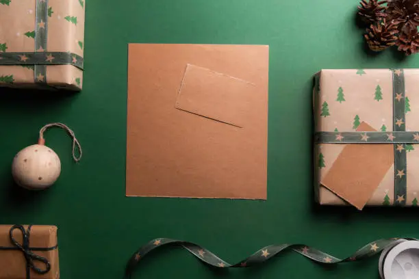 Unwritten vintage brown paper on a green background, surrounded by Christmas presents and decorations.
