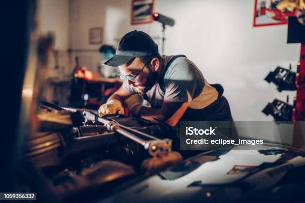 Repair Man Working In Garage On Repair Of Old Timer Stock Photo - Download Image Now