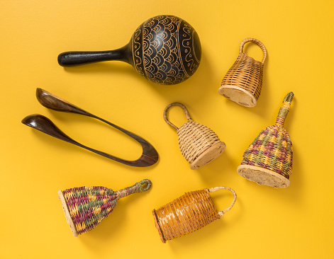 Traditional percussion musical instruments on yellow background. Caxixi shakers, maracas and musical spoons.