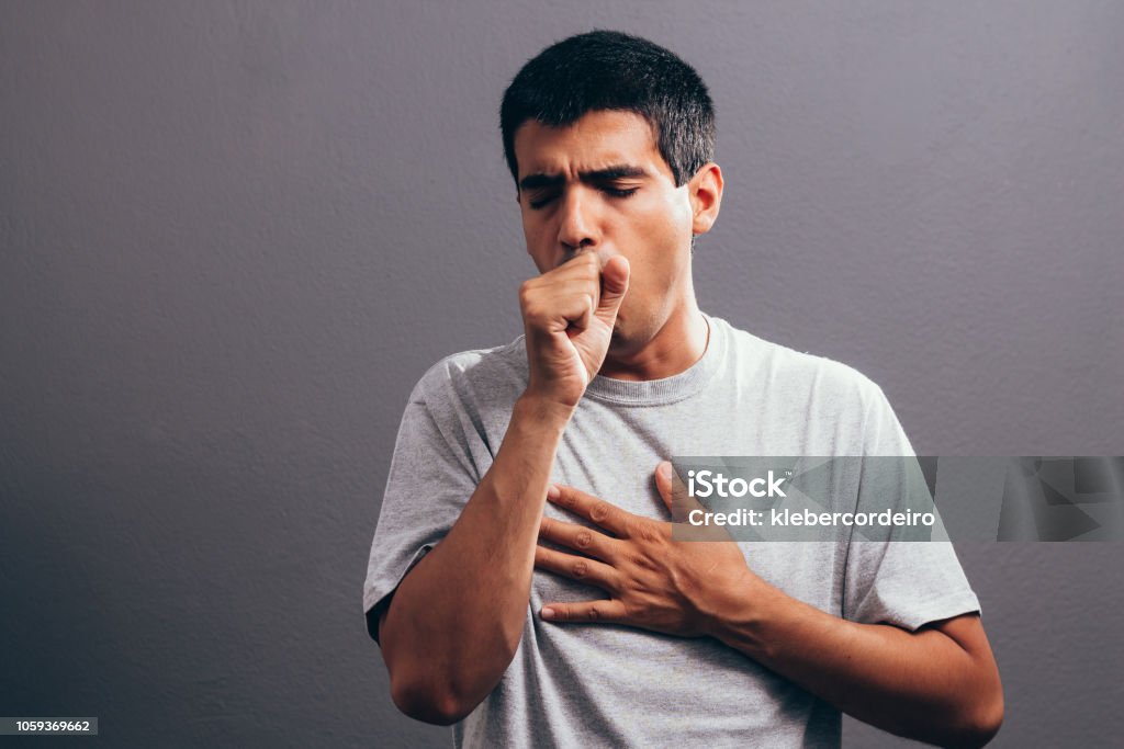 Hombre tosiendo en el puño, aislado sobre un fondo gris - Foto de stock de Toser libre de derechos