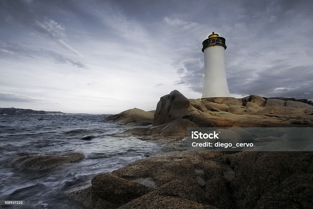 lighthouse lighthouse seen from a tiny beach in Sardinia. Bay of Water Stock Photo
