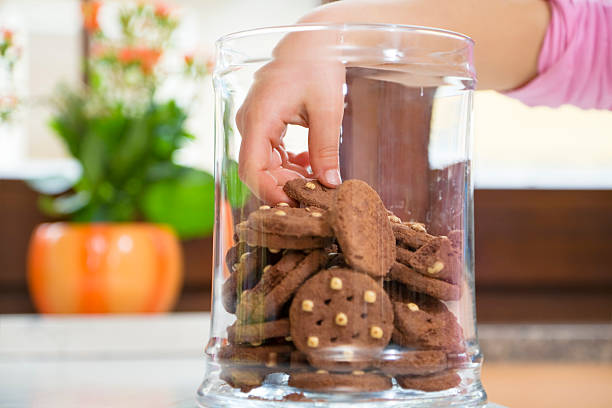 Children's hand in the cookie jar grabbing a cookie stock photo