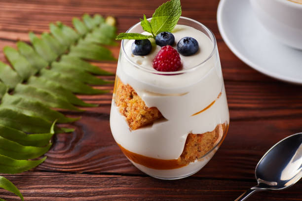 Glass with mascarpone, biscuits, berries dessert Glass with layered dessert with mascarpone, vanilla biscuits and fresh berries tiramisu glass stock pictures, royalty-free photos & images