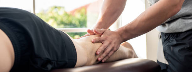 piernas dando terapeuta masculino masaje paciente atleta en la cama en la clínica - massaging men swedish culture male fotografías e imágenes de stock