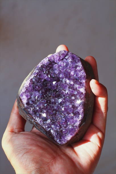 istock Hand holding purple amethyst crystal gemstone 1059390980