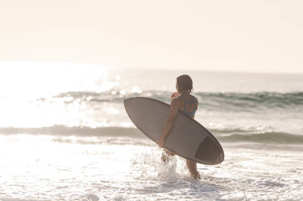 istock Solo woman standing in ocean getting ready to surf 1059392744