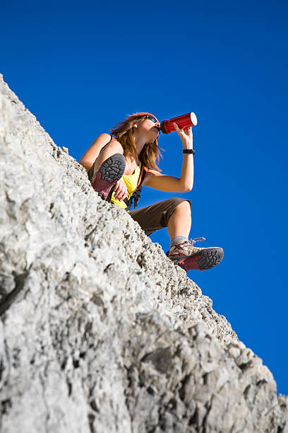 hiking young woman drinking from flask on top of the mountain varigotti stock pictures, royalty-free photos & images