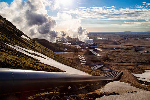 Hellisheidi geothermal powerplant in iceland, shot in evening sun in spring. Pipes leading to the power plant in the distance