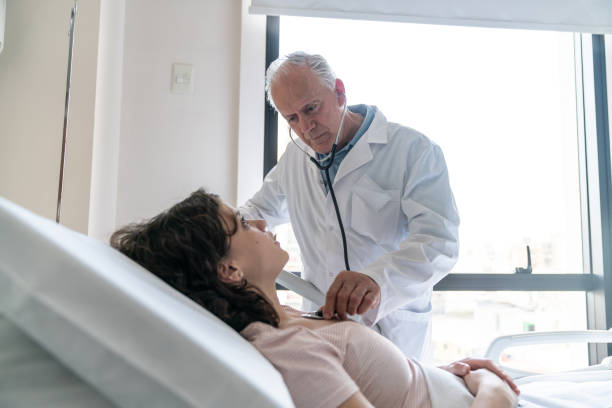 istock Doctor checking patient's heart with stethoscope while lying down on hospital bed 1059416490