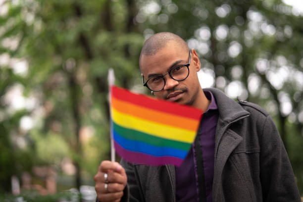 hombre gay ondeando la bandera del arco iris - gay pride flag gay pride gay man homosexual fotografías e imágenes de stock