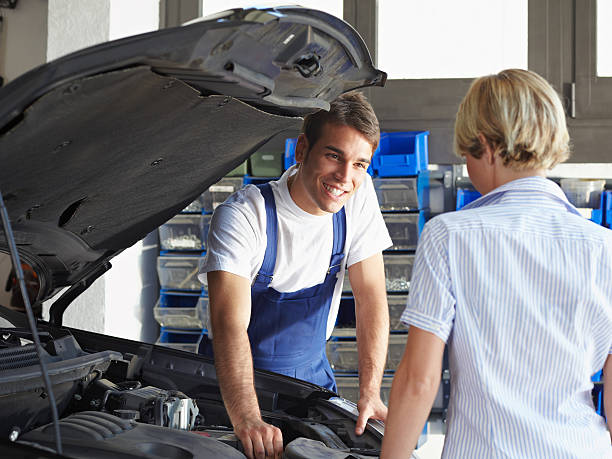 istock Young male mechanic smiling at a lady while fixing her car 105942183