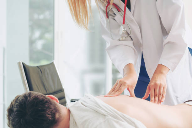 woman doctor and male patient in hospital office - physical injury backache occupation working imagens e fotografias de stock