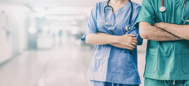 Doctor and surgeon with arms crossed in hospital. Two hospital staffs - surgeon, doctor or nurse standing with arms crossed in the hospital. Medical healthcare and doctor service. paramedic photos stock pictures, royalty-free photos & images