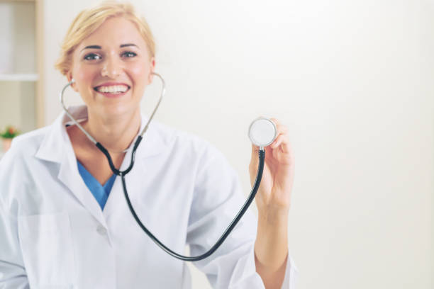 Young female doctor pointing stethoscope at blank space. Selective focus at doctors hand. Medical healthcare concept.