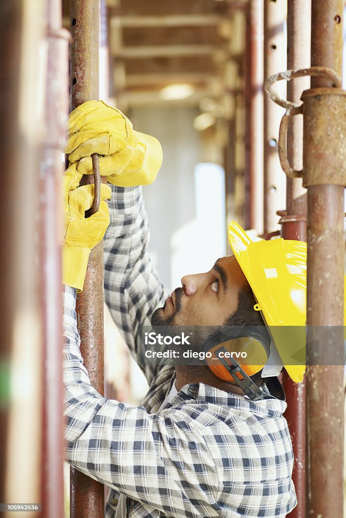 construction worker latin american construction worker fastening girder. Side view Construction Industry Stock Photo