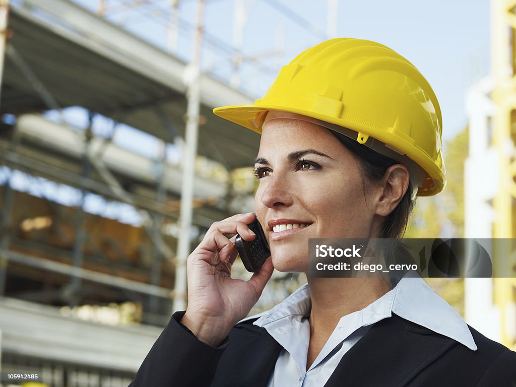 Young female engineer in a hard hat on the phone female engineer talking on mobile phone in construction site Business Stock Photo