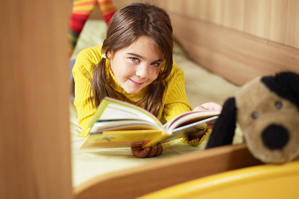 istock Smiling girl on bed with book 105942550