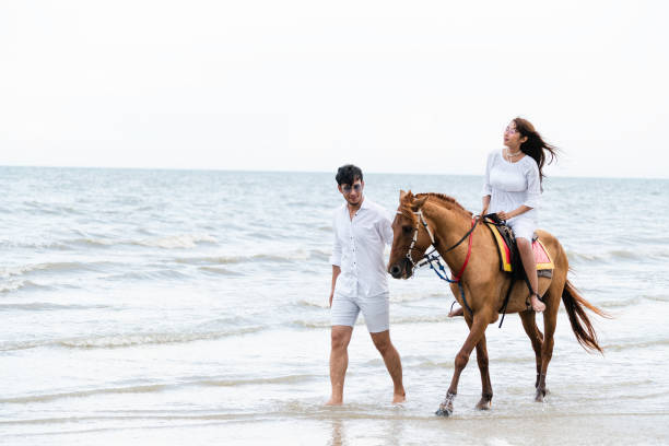 istock Young couple goes horse riding on tropical beach. 1059426444