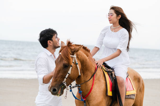 istock Young couple goes horse riding on tropical beach. 1059426504