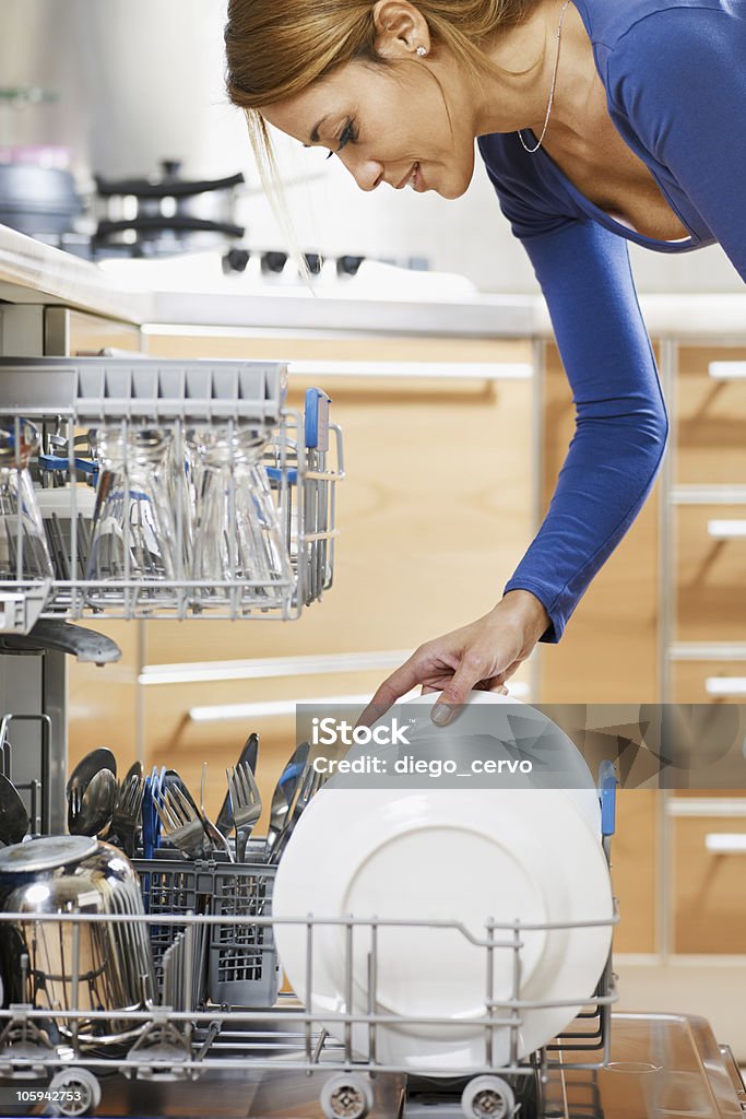 woman using dishwasher side view of young woman in kitchen doing housework Dishwasher Stock Photo