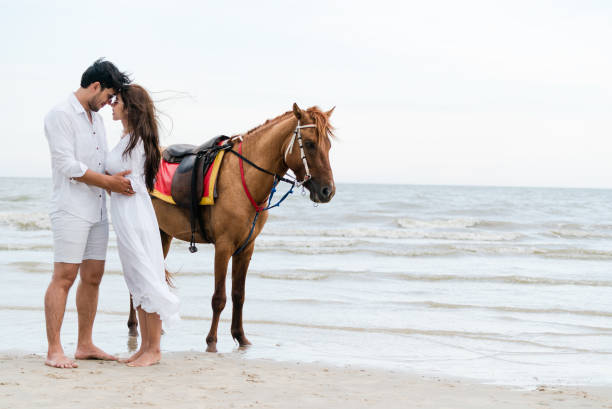 istock Young couple goes horse riding on tropical beach. 1059427558