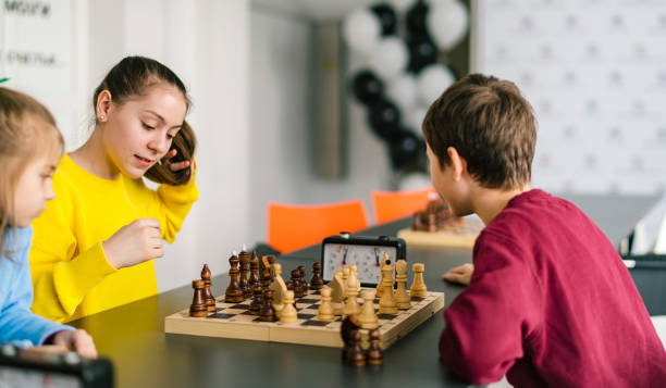 Kids of different ages, boys and girls, playing chess on the tournament in the chess club Kids of different ages, boys and girls, playing chess on the tournament in the chess club chess timer stock pictures, royalty-free photos & images