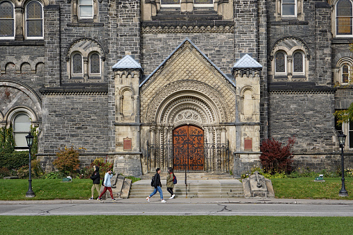Toronto, Canada - October 25, 2018:  Students walking on the University of Toronto's campus, which has numerous gothic buildings in a park like setting in the downtown area of the city.