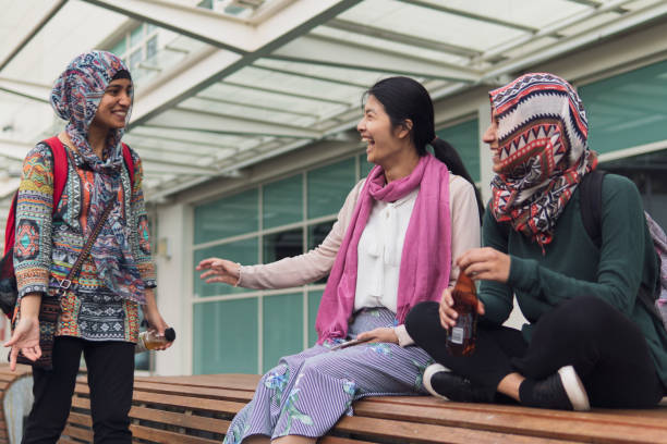 istock Muslim University student greeting her friends sitting outside on a bench 1059437260