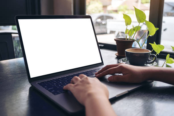 istock Mockup image of a woman's hands using and typing on laptop with blank white desktop screen with coffee cup on wooden table in cafe 1059442160
