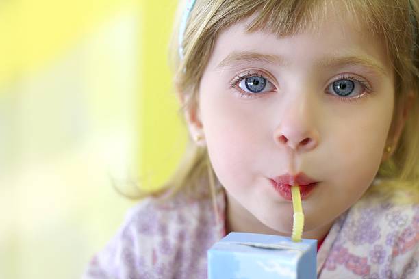 blond little girl drinking straw container blond little girl drinking straw tetra brick blue eyes juice carton stock pictures, royalty-free photos & images