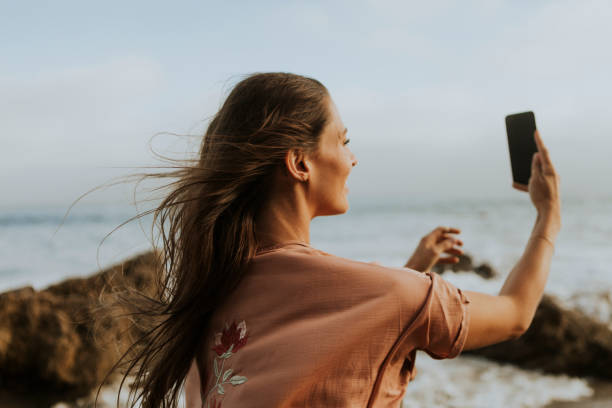 istock Cheerful woman taking selfie by the beach 1059451172