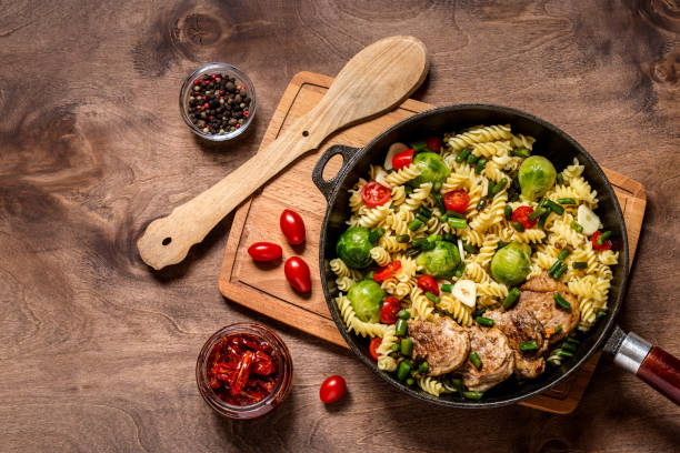 istock Pasta with vegetables in cast iron pan on wooden background 1059452948